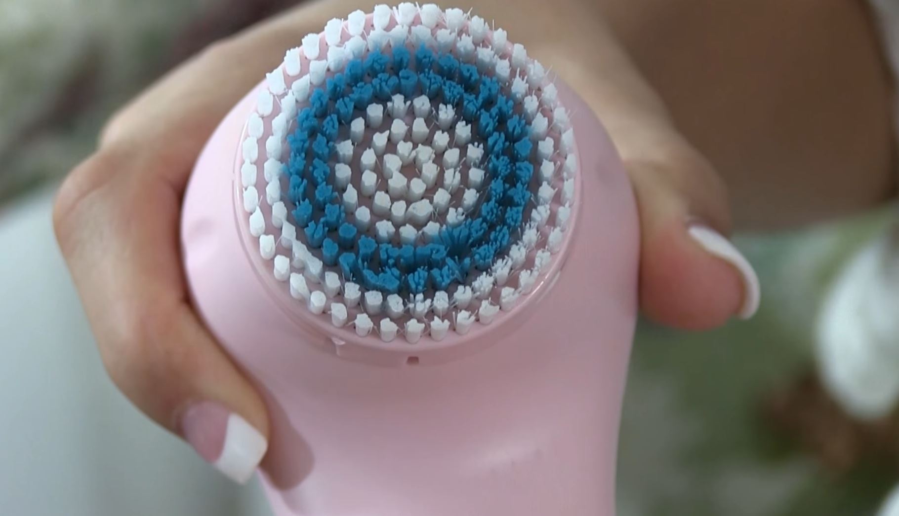 woman's hands holding pink erisonic facial brush